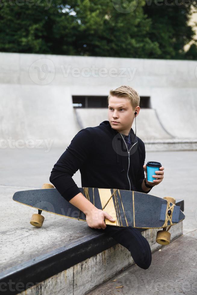 portatori di handicap tipo con un' tazza di caffè prima longboard equitazione nel un' Skate park foto