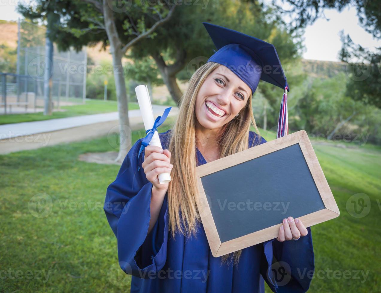 donna Tenere diploma e vuoto lavagna indossare berretto e toga foto