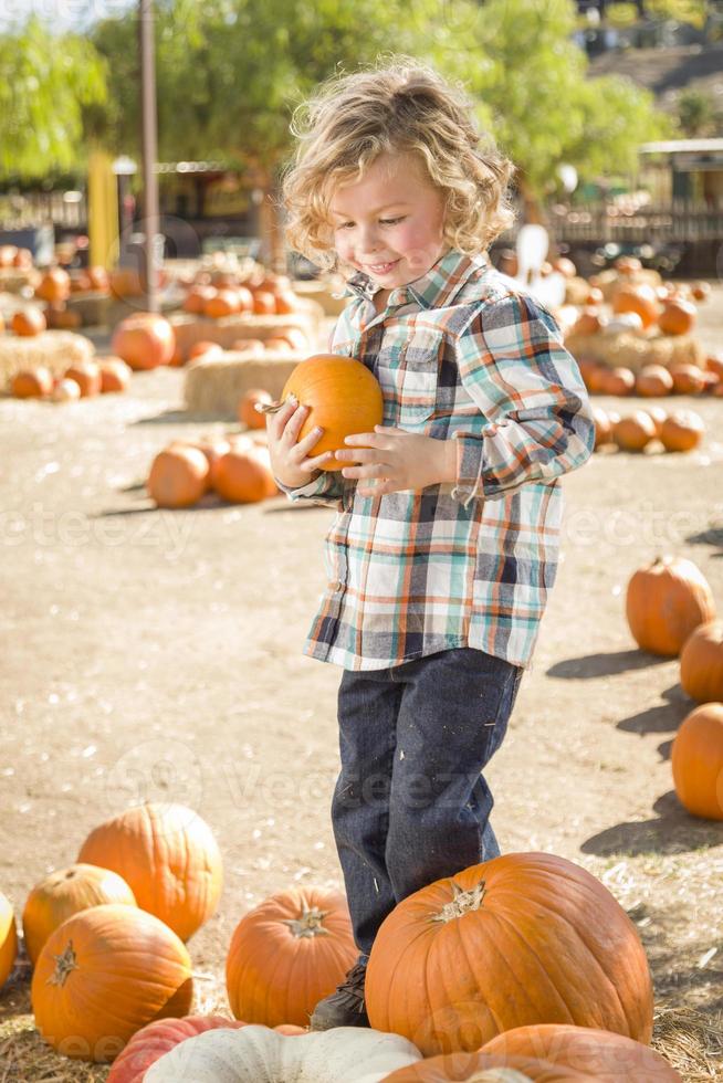 poco ragazzo Tenere il suo zucca a un' zucca toppa foto