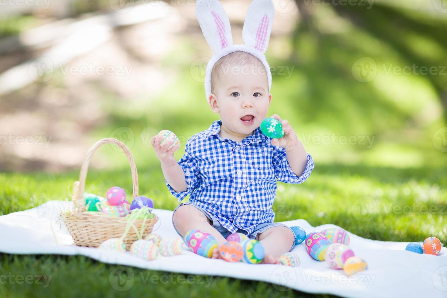misto gara Cinese e caucasico bambino ragazzo al di fuori indossare coniglio orecchie giocando con Pasqua uova foto