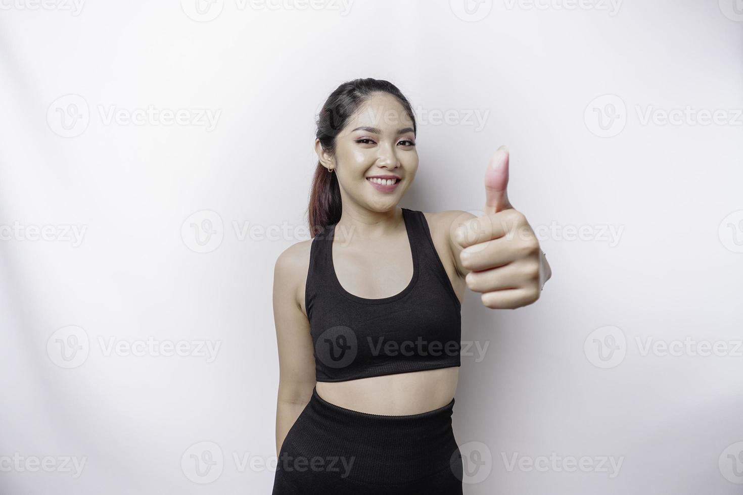 eccitato sportivo asiatico donna indossare abbigliamento sportivo dà pollici su mano gesto di approvazione, isolato di bianca sfondo foto