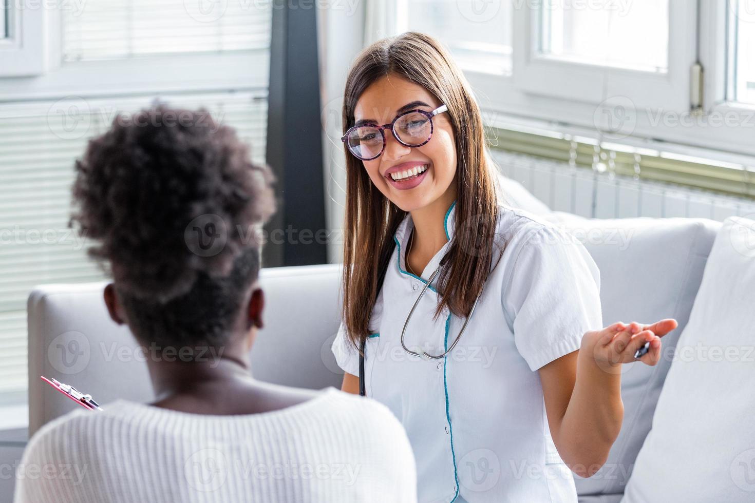 sorridente paziente nel il medico ufficio, lei è ricevente un' prescrizione medicinale, affascinante femmina medico dando consigli per un' femmina paziente. foto