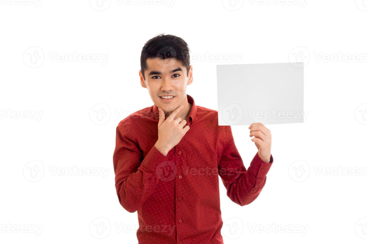 bello giovane brunetta uomo in posa con vuoto cartellone nel il suo mani e sorridente su telecamera isolato su bianca sfondo foto