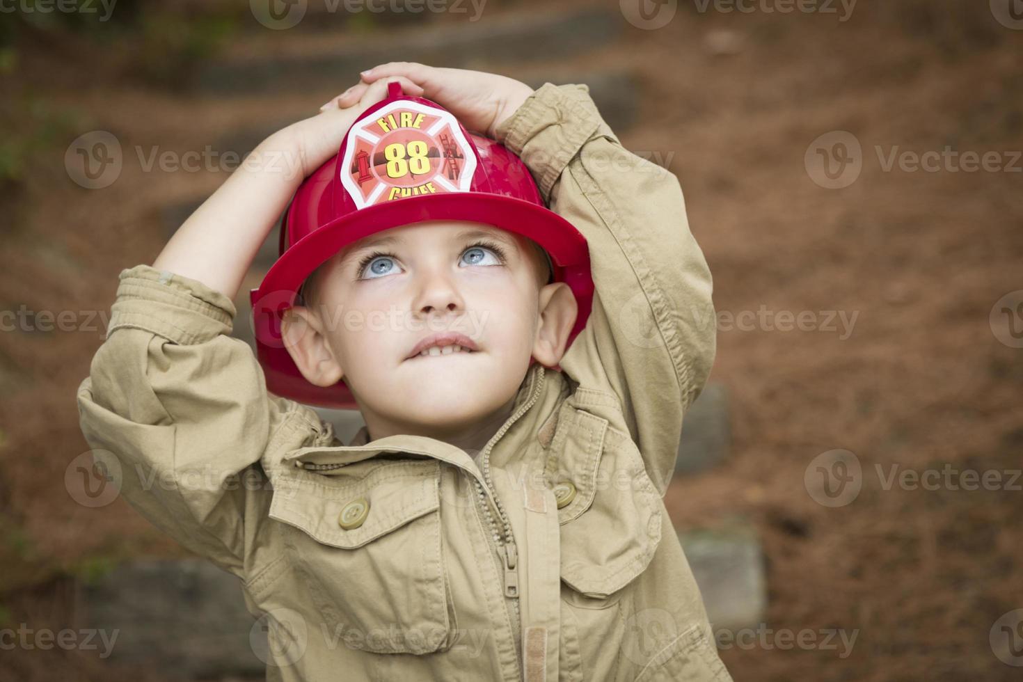 adorabile bambino ragazzo con vigile del fuoco cappello giocando al di fuori foto