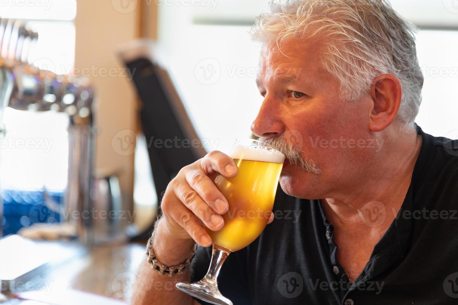 bello uomo degustazione un' bicchiere di micro infuso birra foto