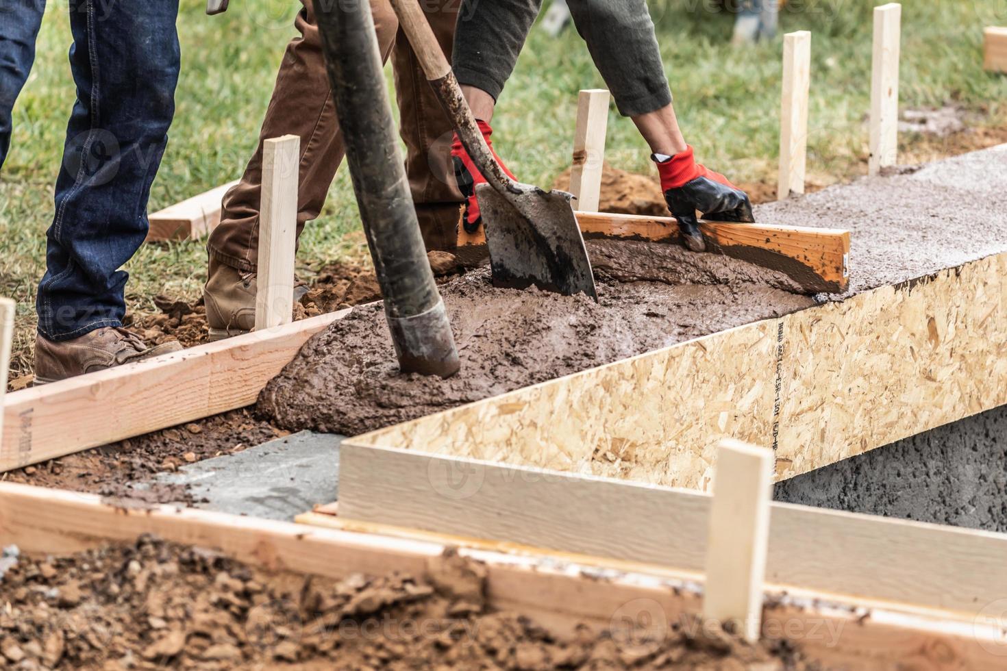 costruzione lavoratori scrosciante e livellamento bagnato cemento in legna inquadratura foto