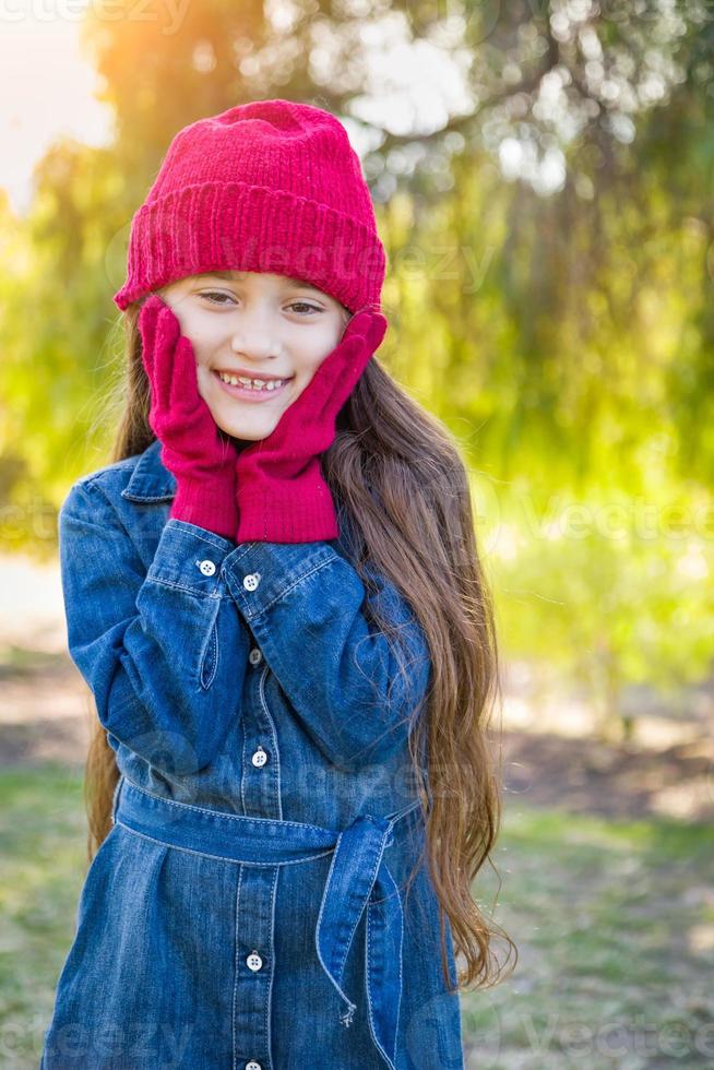 carino misto gara giovane ragazza indossare rosso maglia berretto e guanti all'aperto foto