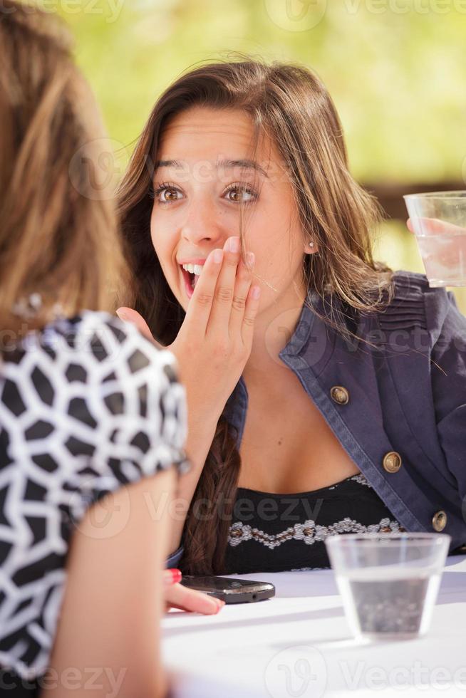 espressive giovane adulto donna avendo bevande e parlando con sua amico all'aperto foto