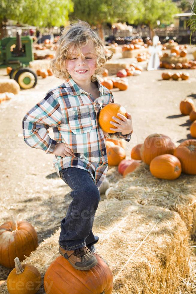 poco ragazzo Tenere il suo zucca a un' zucca toppa foto