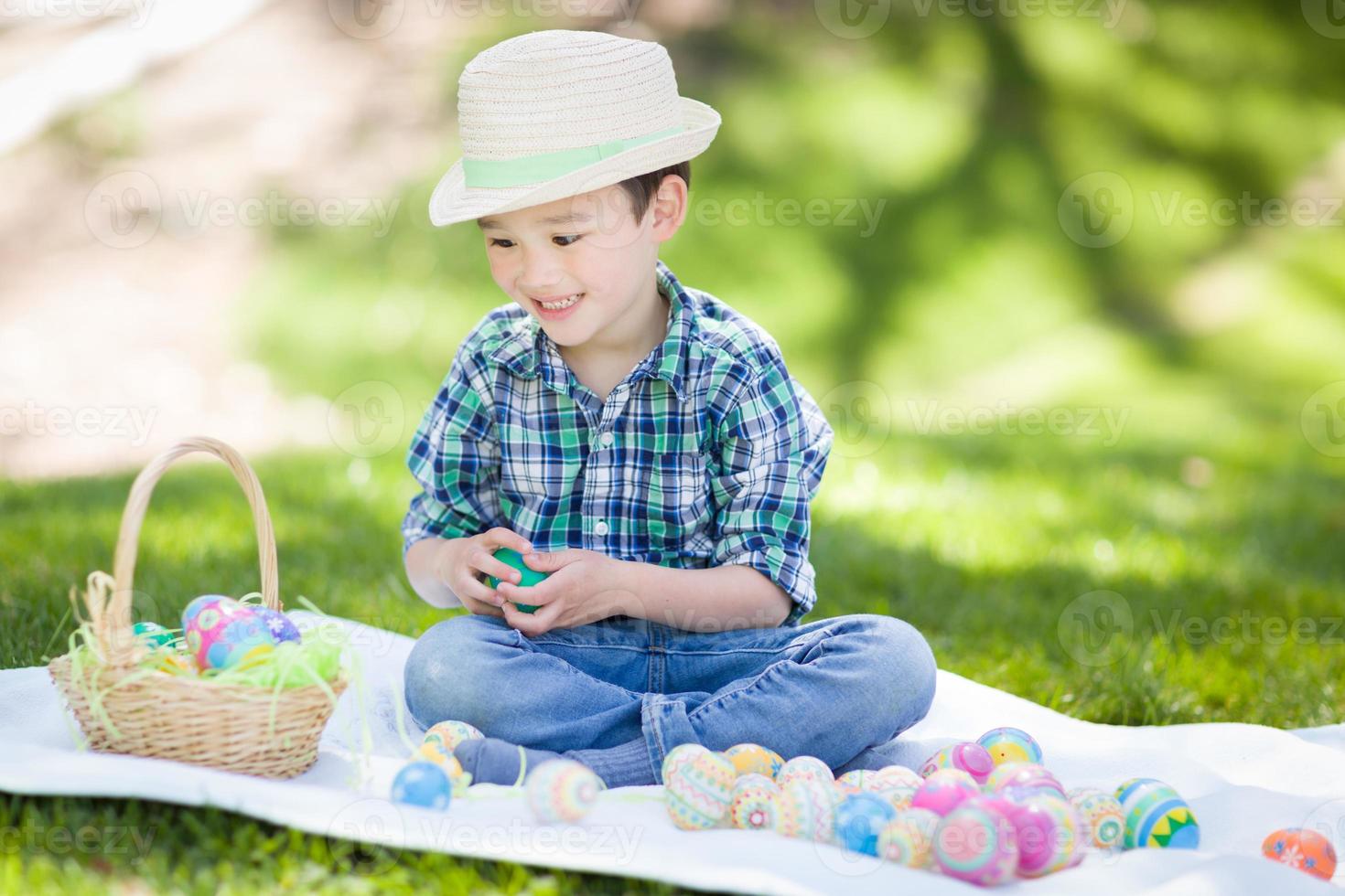 misto gara Cinese e caucasico ragazzo al di fuori indossare coniglio orecchie giocando con Pasqua uova foto