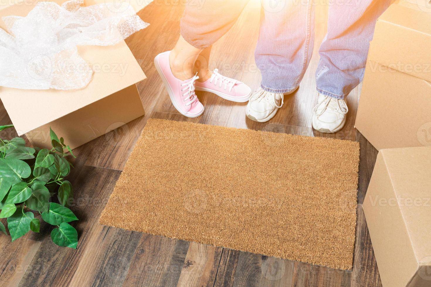 uomo e donna in piedi vicino casa dolce casa benvenuto stuoia, in movimento scatole e pianta foto