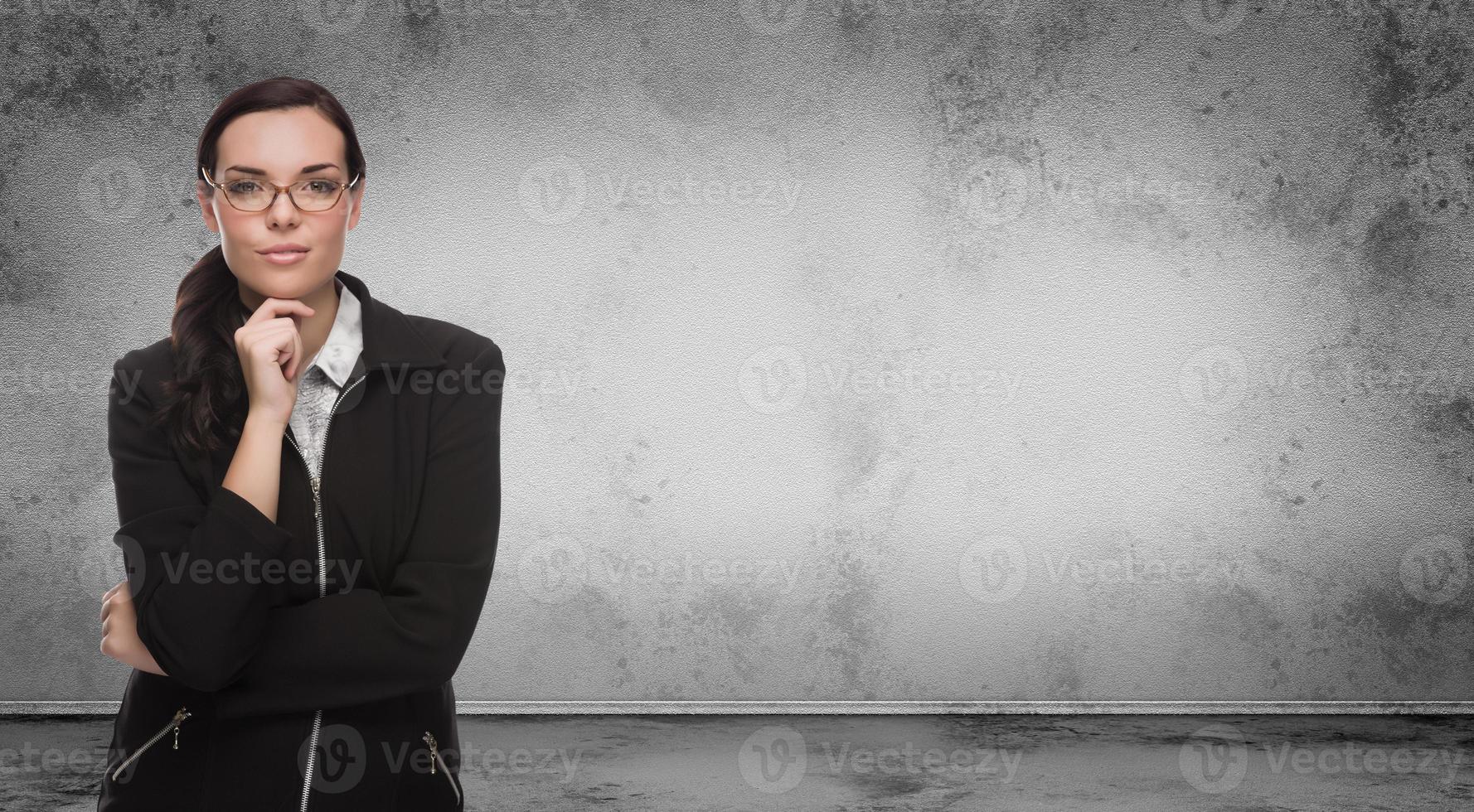 giovane adulto donna con matita e bicchieri in piedi nel davanti di vuoto grungy vuoto parete con copia spazio foto