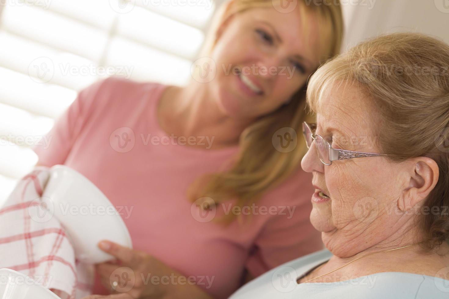 anziano adulto donna e giovane figlia parlando nel cucina foto