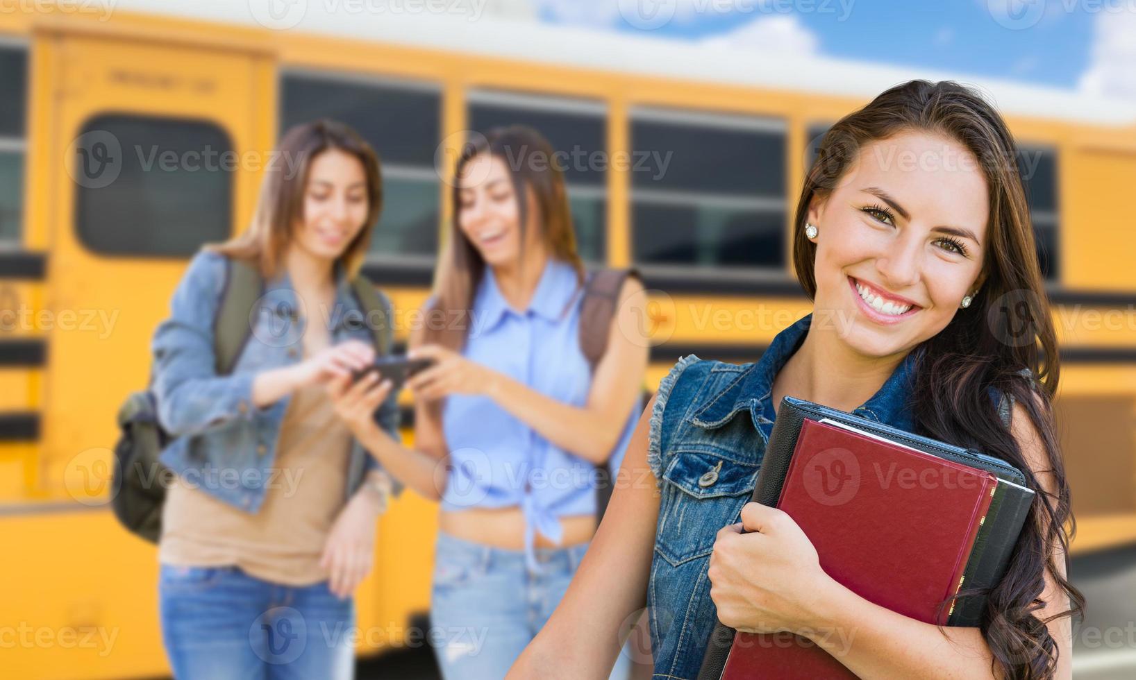giovane femmina alunno con libri vicino scuola autobus foto