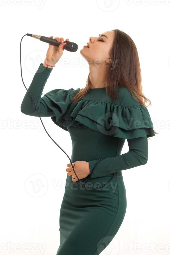 affascinante giovane ragazza nel verde vestito cantando un' karaoke foto