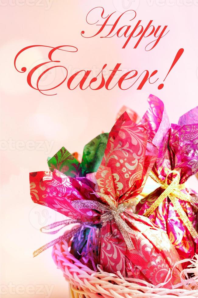 Pasqua carta - uova avvolto nel colore carta vicino su su rosa, parole contento Pasqua e bokeh luci. foto