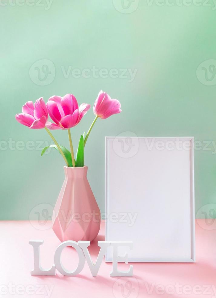 rosa tulipani nel vaso, vuoto bianca telaio, bianca lettere amore su pastello rosa verde sfondo. finto su. foto