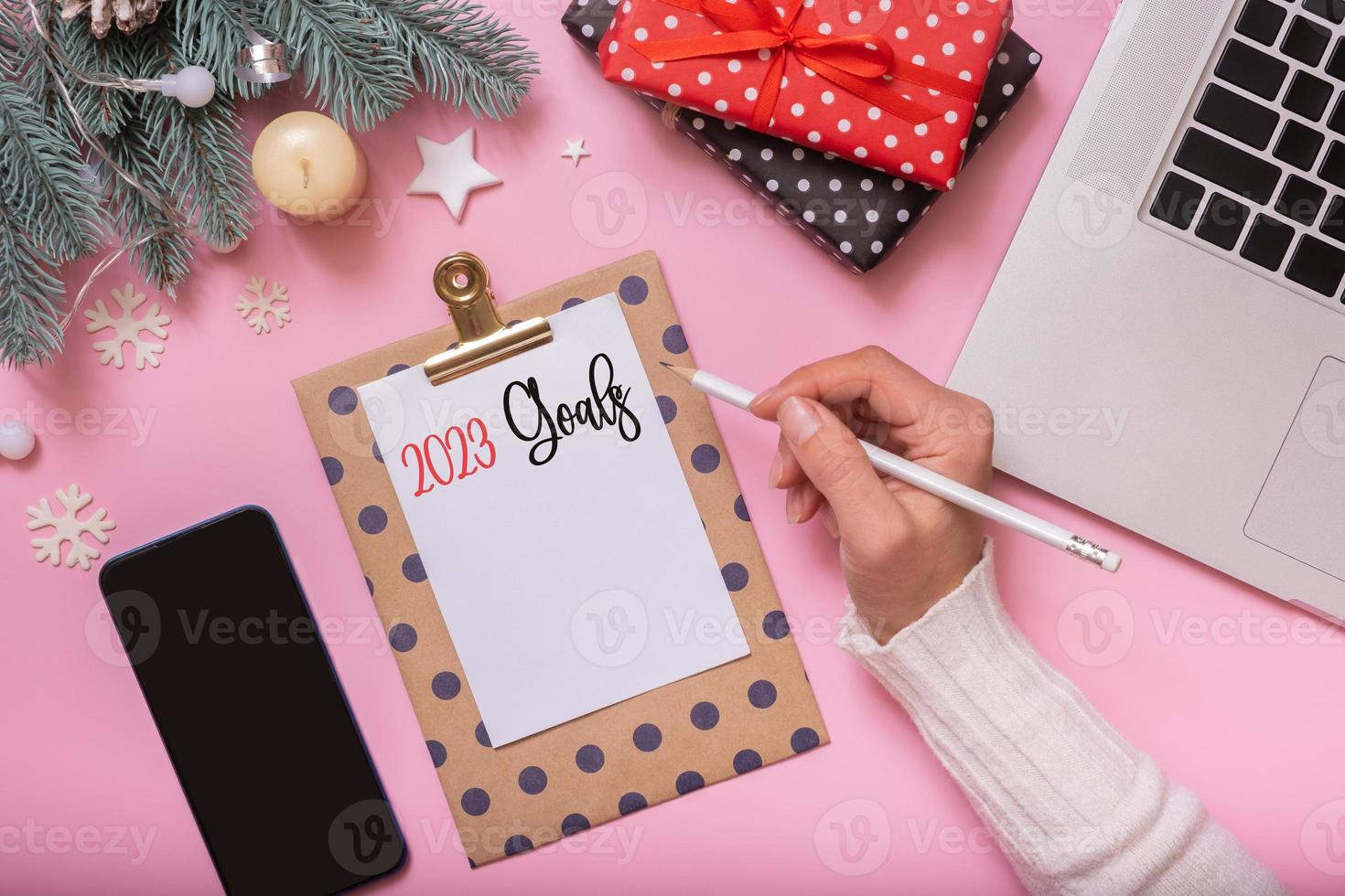 2023 obiettivi femmina mano Scrivi e natale nuovo anno opera tavolo decorazione superiore Visualizza, piatto posare su rosa sfondo foto