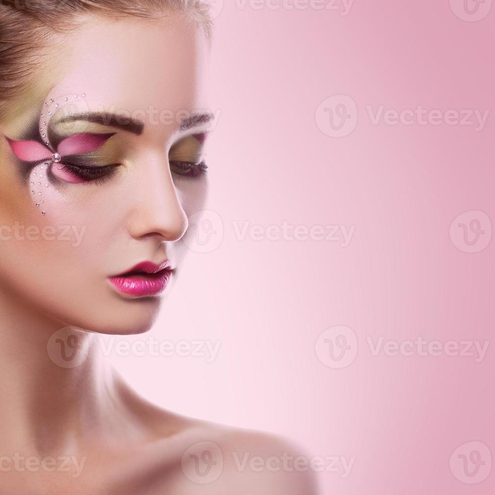 giovane adulto donna con chiuso occhi e creativo trucco su rosa sfondo foto