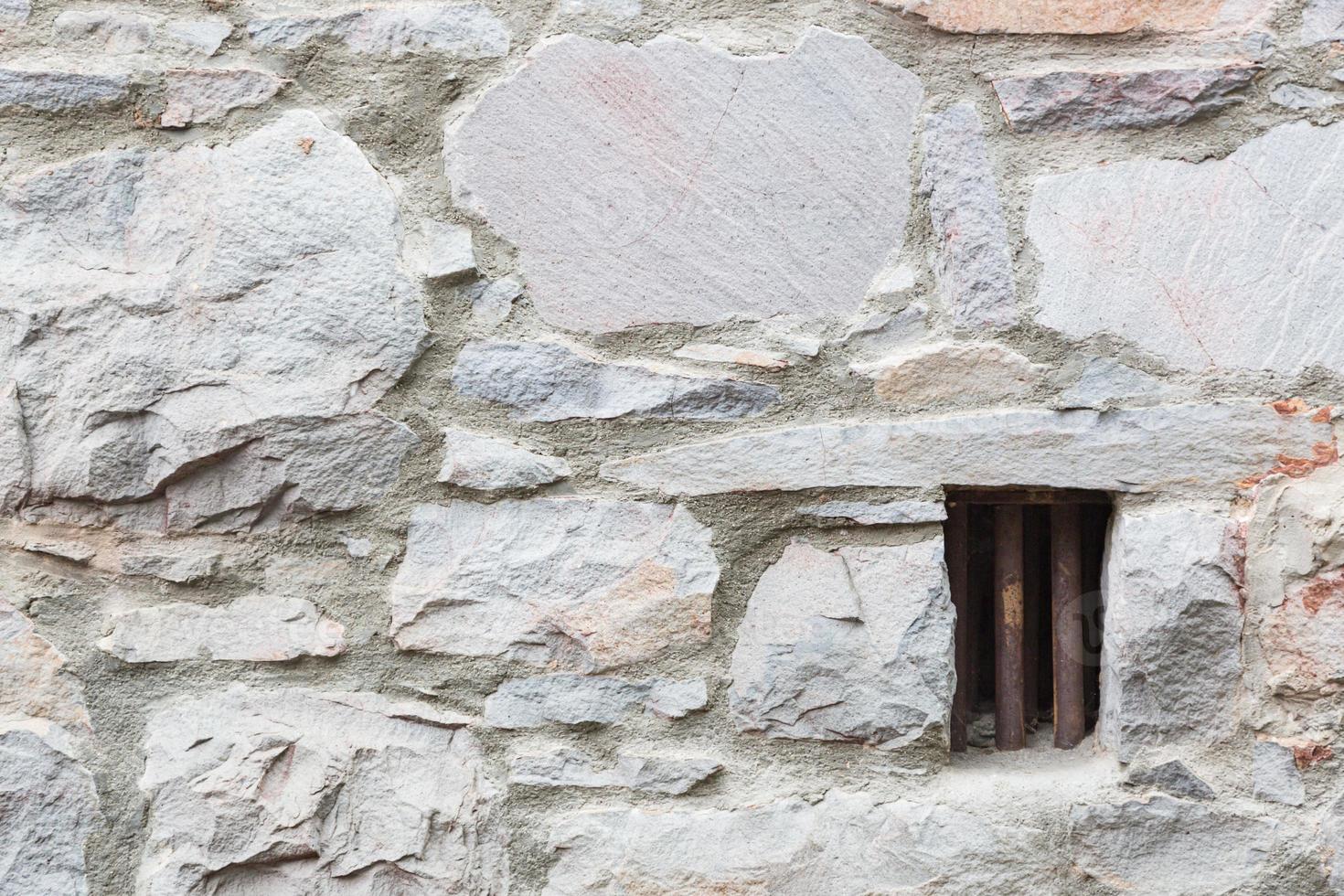 vecchio pietra parete con piccolo ferro sbarrato prigione cellula finestra foto