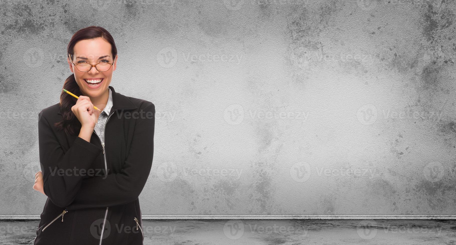 giovane adulto donna con matita e bicchieri in piedi nel davanti di vuoto grungy vuoto parete con copia spazio foto