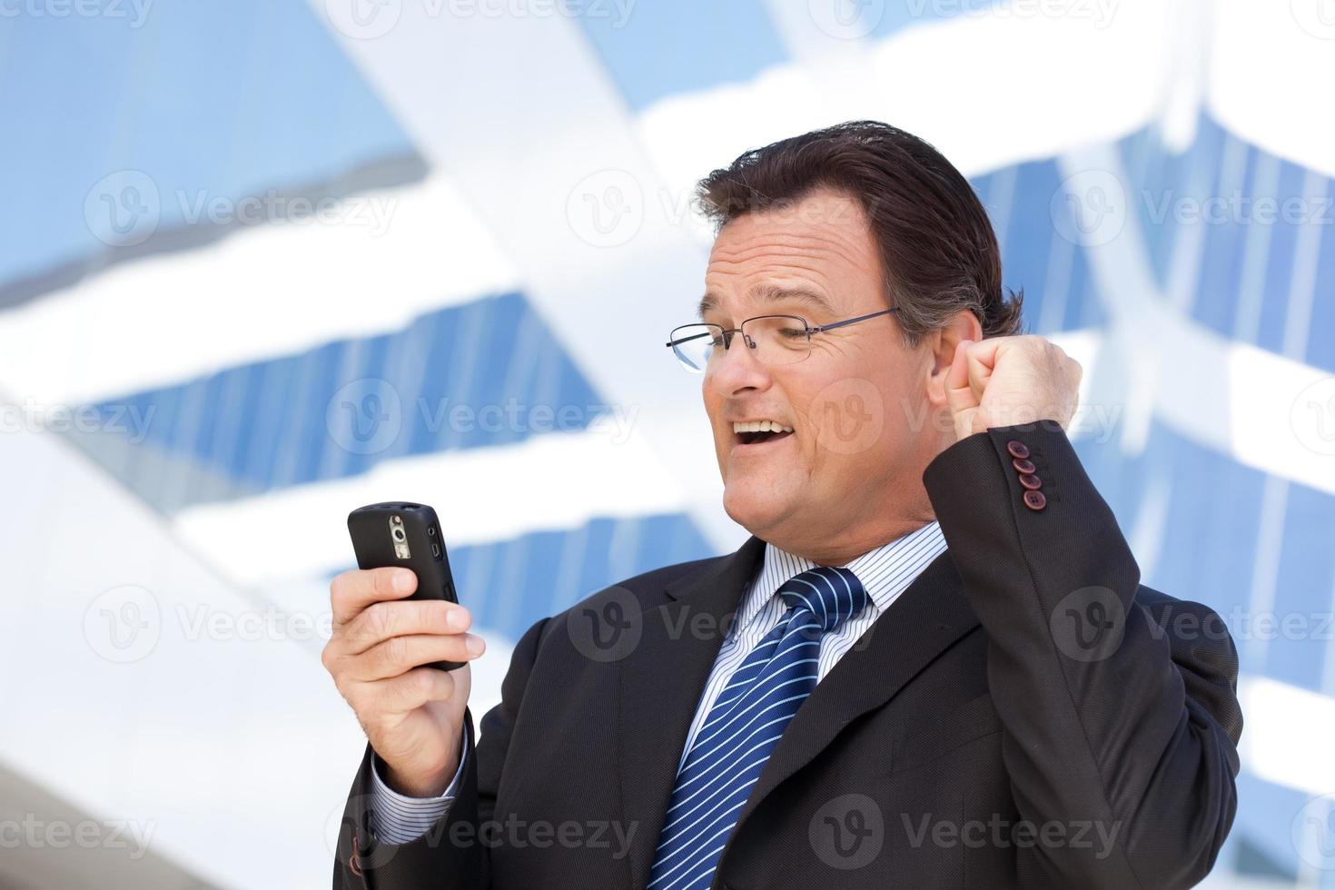 uomo d'affari guardare a cellula Telefono ribadisce il suo cazzotto nel gioia foto