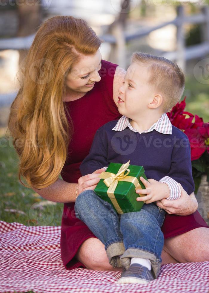 giovane ragazzo Tenere Natale regalo con il suo mamma nel parco foto