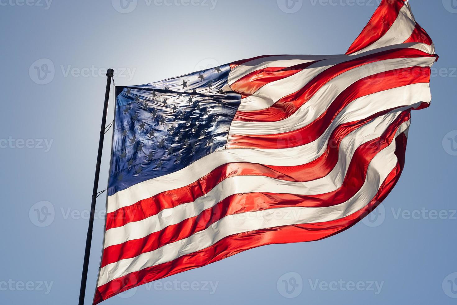 retroilluminato americano bandiera agitando nel vento contro un' in profondità blu cielo foto