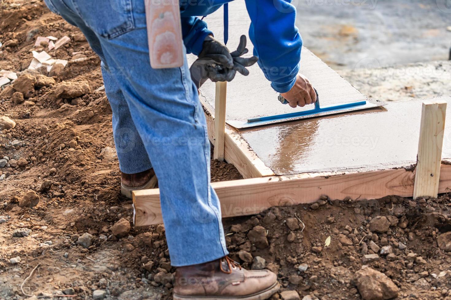 costruzione lavoratore utilizzando cazzuola su bagnato cemento formatura cimasa in giro nuovo piscina foto