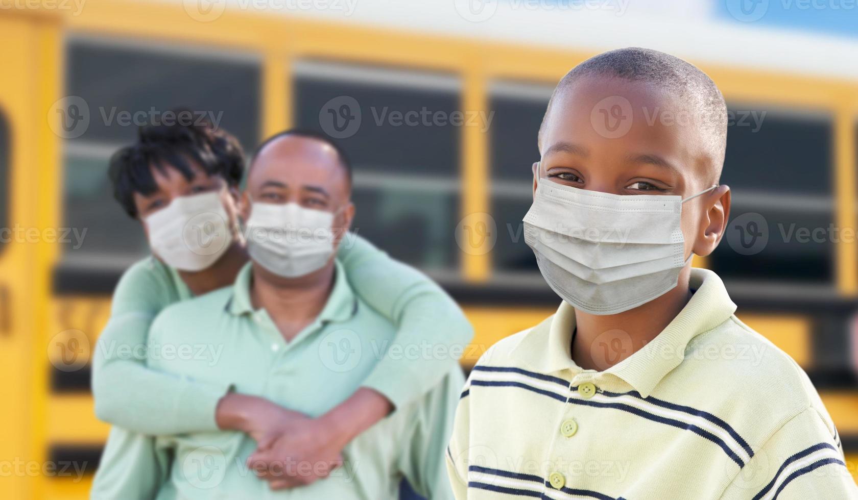 giovane africano americano alunno e genitori vicino scuola autobus indossare medico viso maschere durante coronavirus pandemia foto