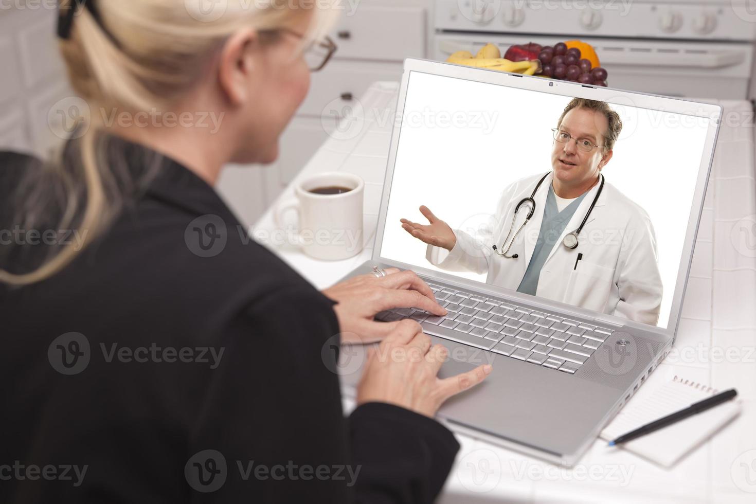 donna nel cucina utilizzando il computer portatile - in linea con infermiera o medico foto