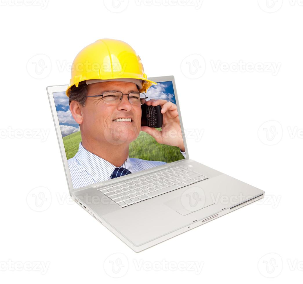 il computer portatile e uomo con difficile cappello su cellula Telefono foto