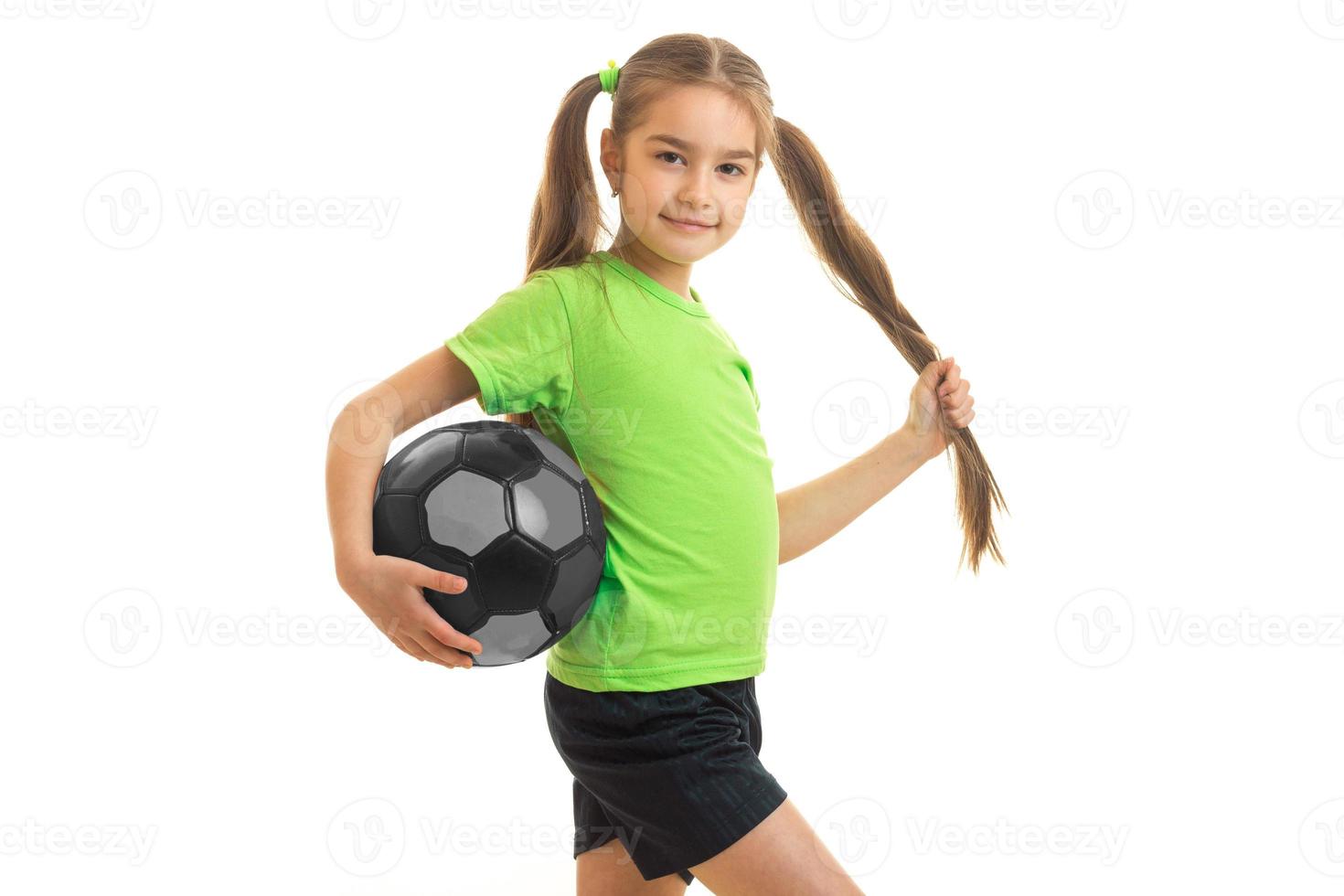 poco carino ragazza nel verde camicia con calcio palla nel mani foto