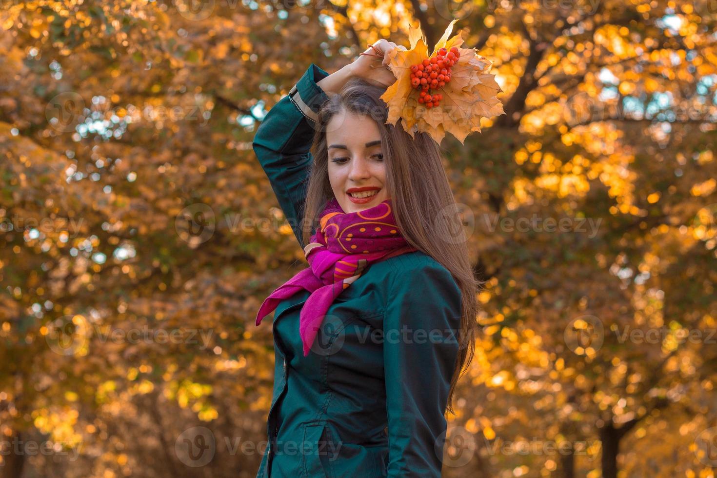 sorridente giovane ragazza sollevato sua mano con il le foglie sopra testa e chiuso occhi foto