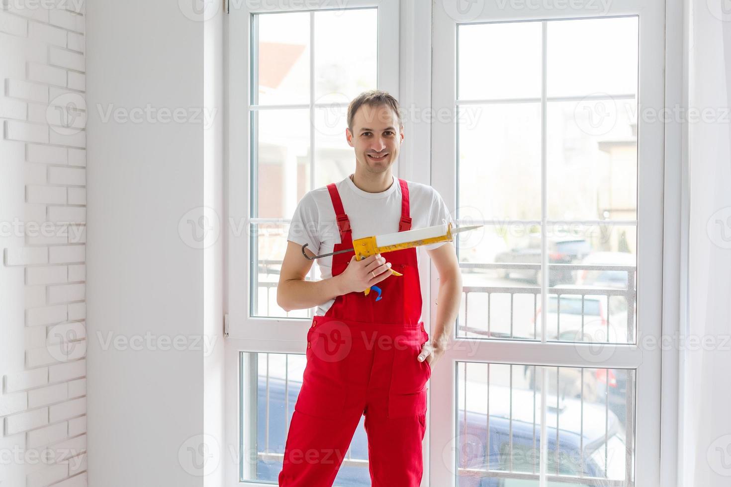 lavoratore nel tuta da lavoro ambientazione su nuovo finestre nel il ufficio foto