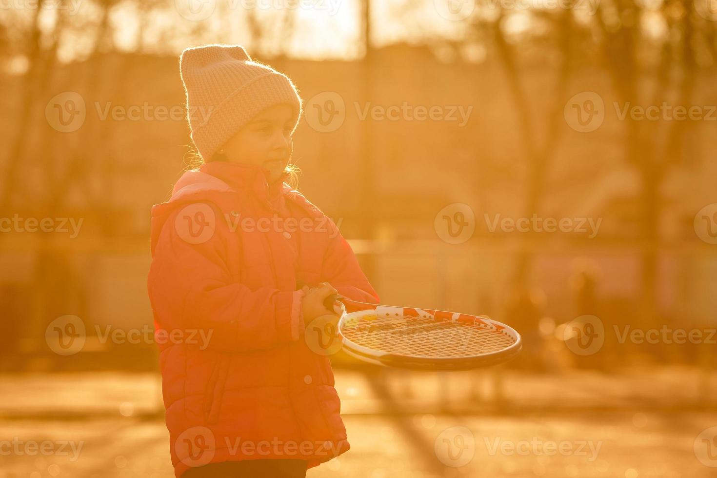 poco ragazza apprendimento per colpire il tennis sfera. poco ragazza tennis giocatore con palla e racchetta su Tribunale. attivo esercizio per bambini foto