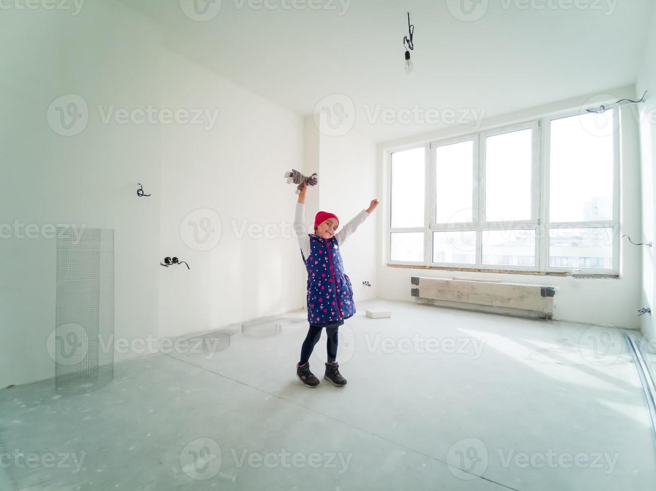 eccitato carino bambino sentire spensierato avendo divertimento trasferimento in nuovo casa, divertente poco ragazza giocando salto godendo mossa nel grande moderno vivente camera foto