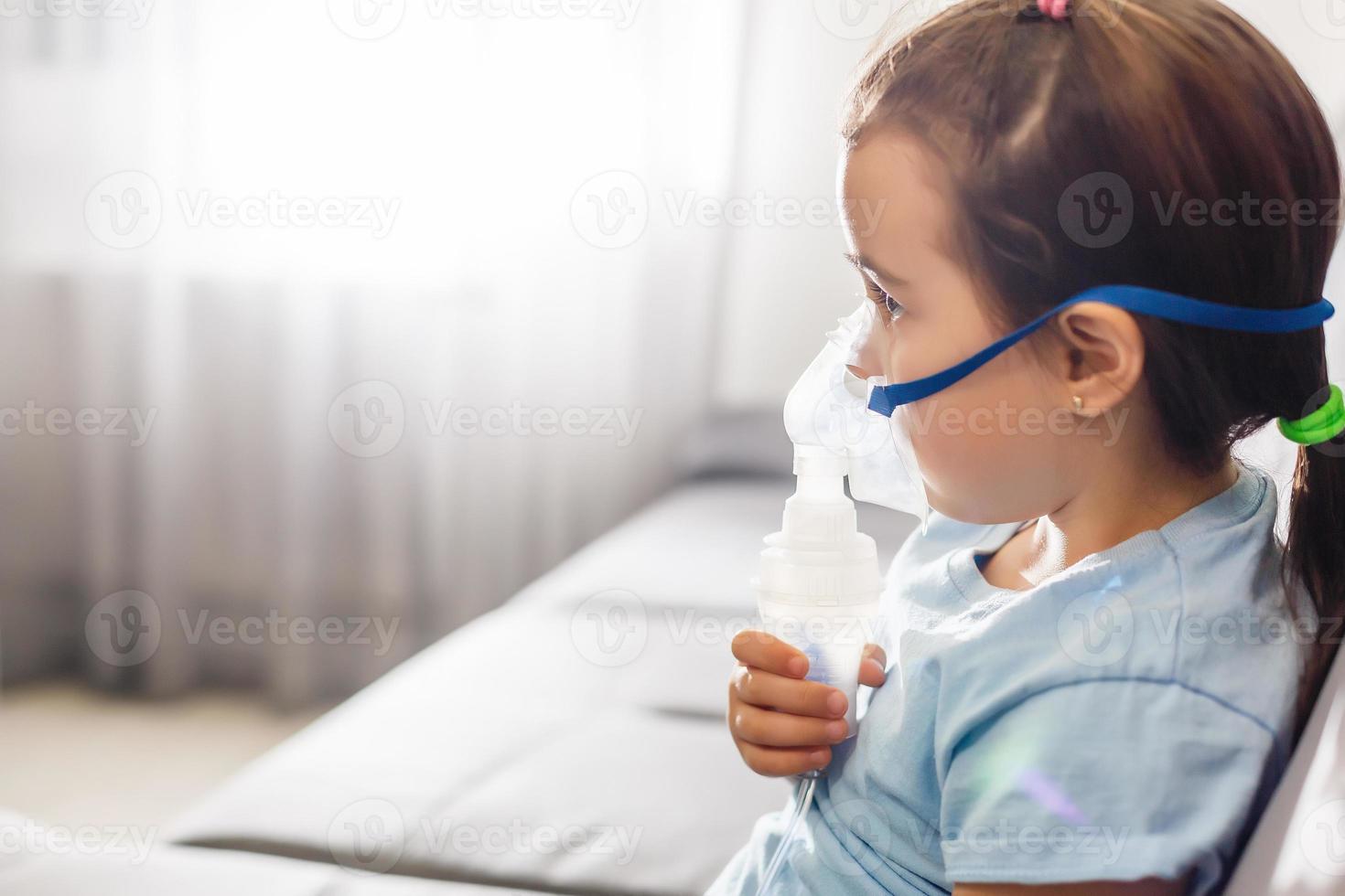 poco ragazza nel un' maschera, trattamenti respiratorio tratto con un' nebulizzatore a casa foto