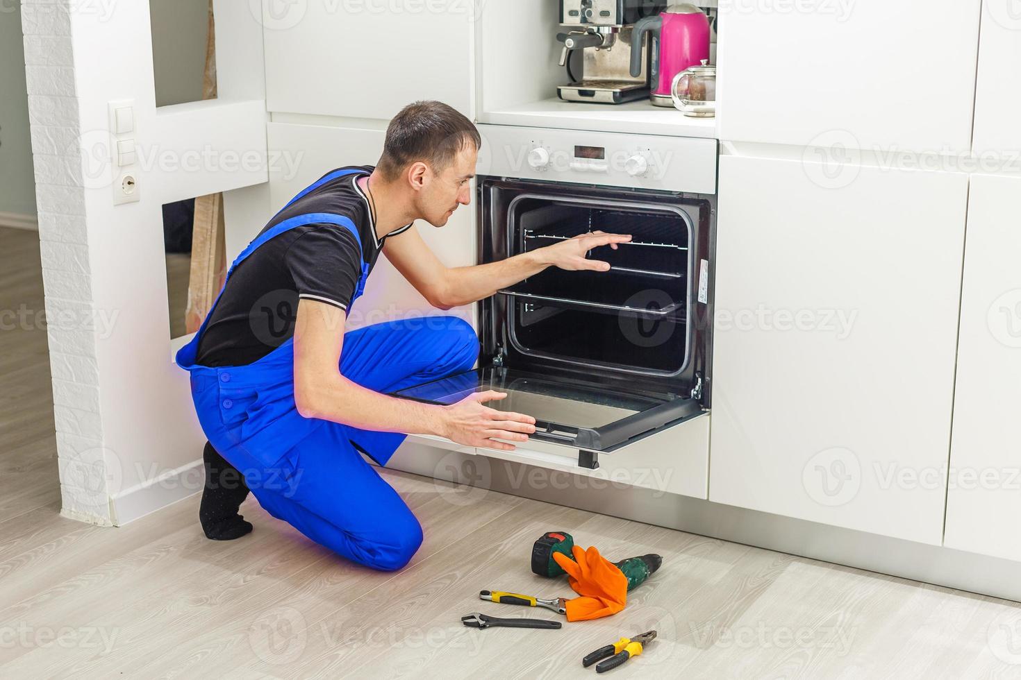 maschio tecnico seduta vicino forno nel cucina foto