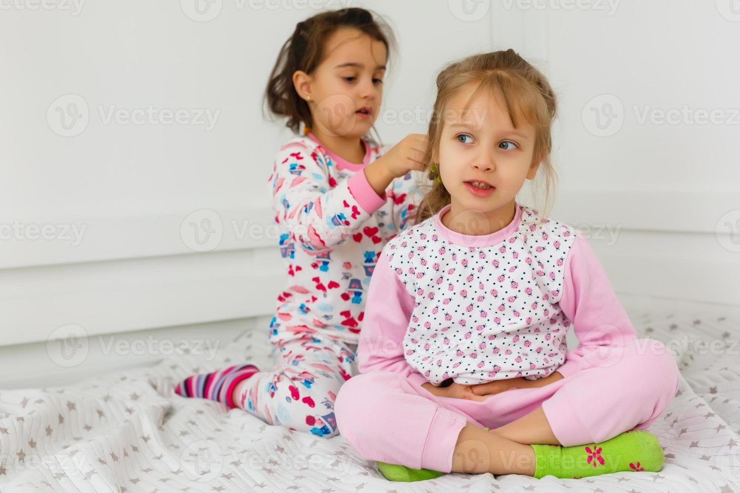 pigiama festa e amicizia. pigiama festa di Due contento piccolo bambini nel Camera da letto. amicizia di piccolo bambini ragazze con contento facce. si. foto