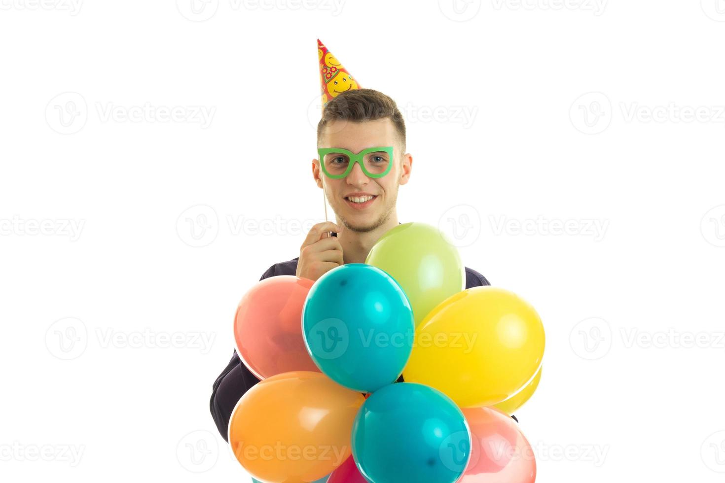 contento giovane uomo con carta bicchieri e palloncini nel mani sorridente su telecamera foto
