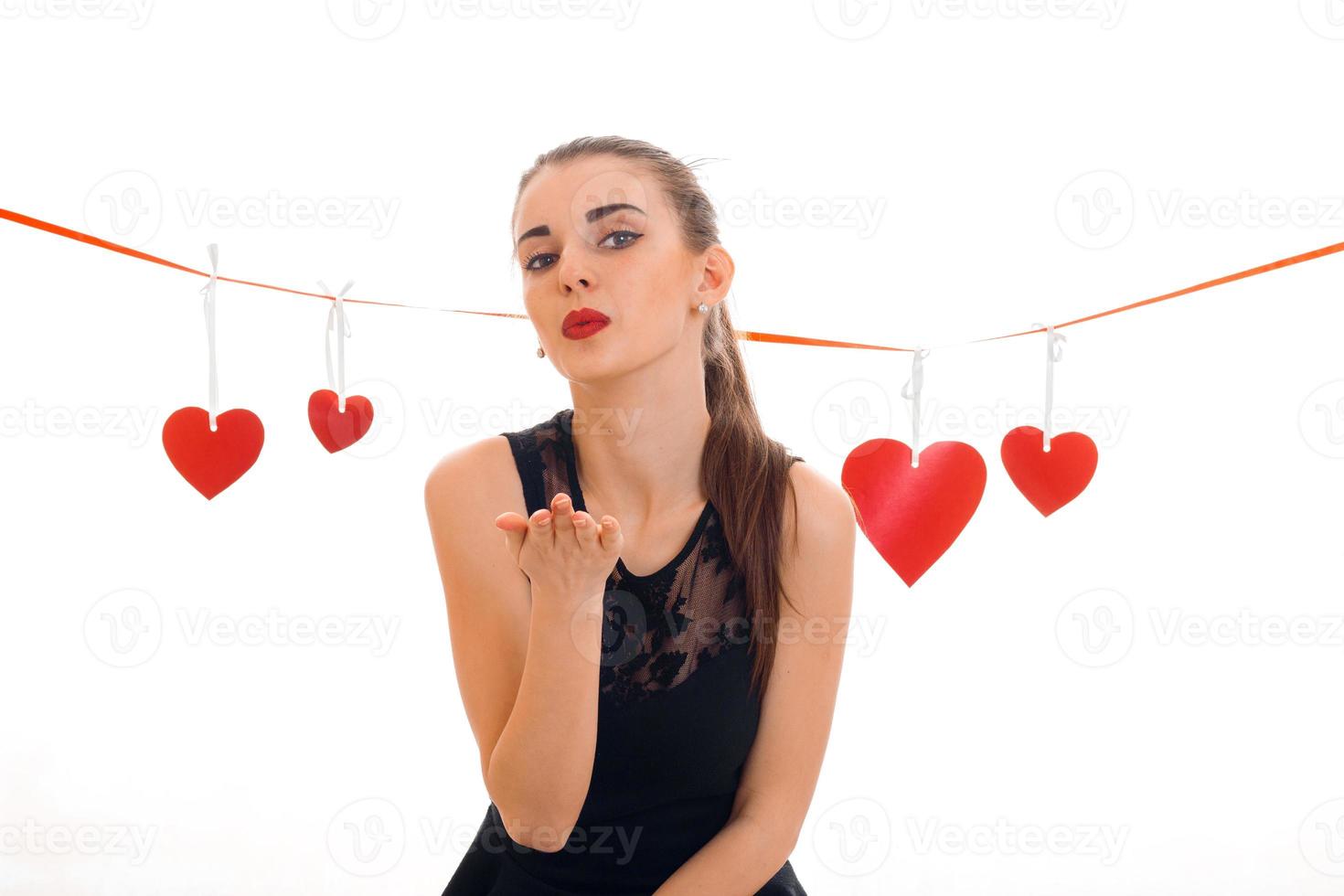 giovane bello donna con rosso labbra preparazione per celebrare san valentino giorno con cuore simbolo nel studio isolato su bianca sfondo foto