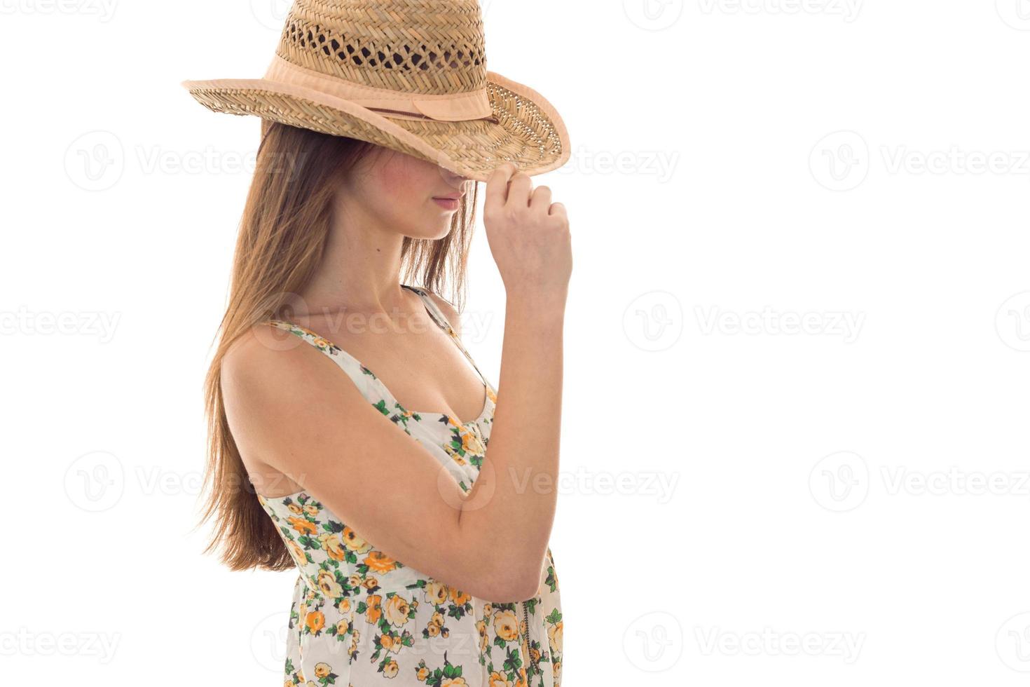 un' giovane ragazza con lungo capelli è di valore svolta lateralmente per il telecamera con il cappello su il tuo testa foto
