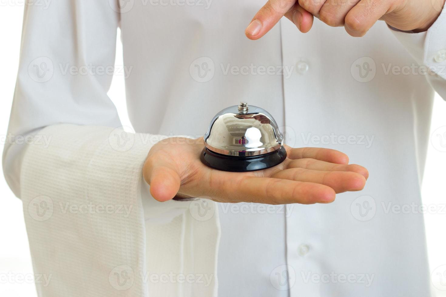 Cameriere nel un' bianca camicia con un' tovagliolo su il mano detiene nel il palme campana avvicinamento foto