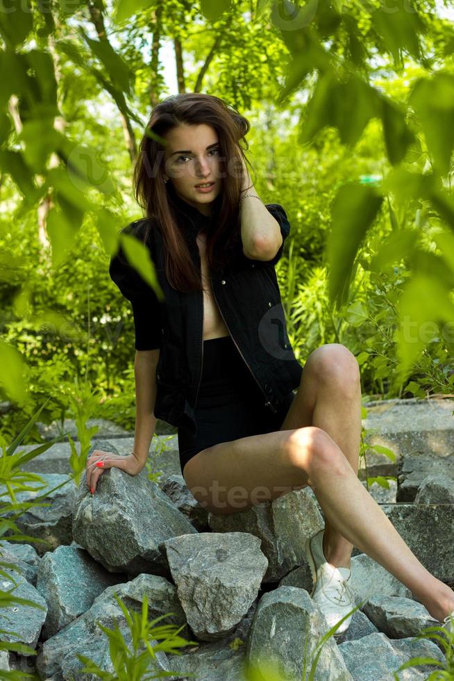 bellissimo ragazza nel nero vestito in posa su il rocce foto