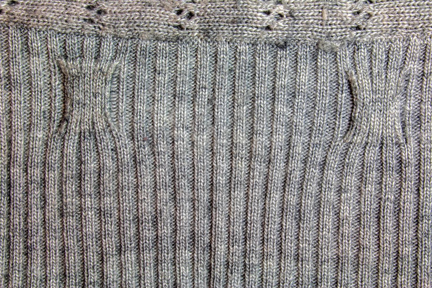 grigio a maglia fatto a mano maglione sfondo. il struttura di il superficie di il di lana maglia fatto di filato, avvicinamento. Immagine per il sfondo. lana tappeto o maglione. grigio struttura. moderno design. foto