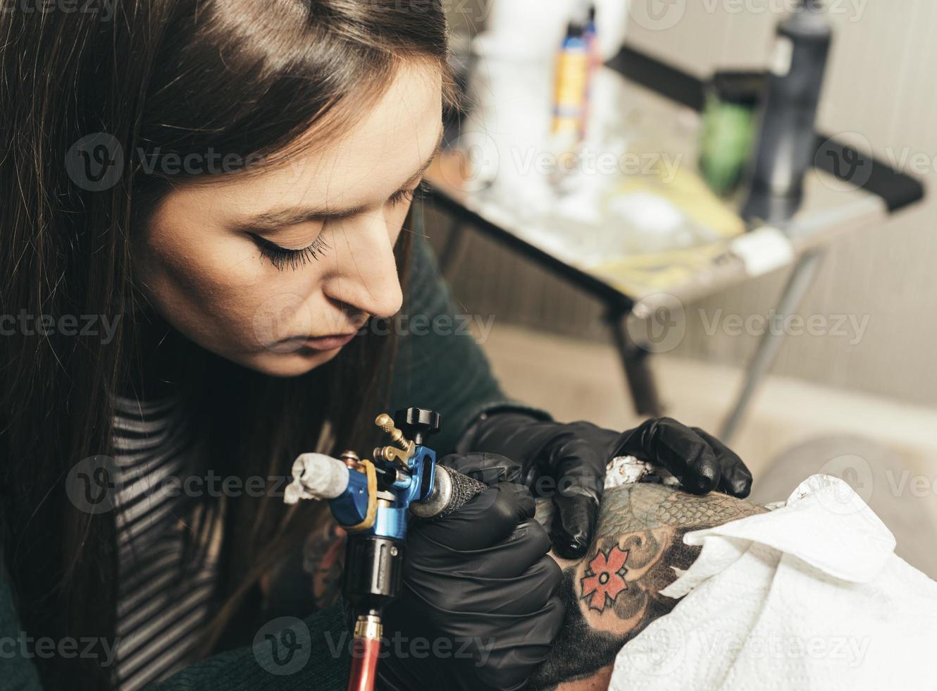 vicino su tatuaggio macchina. donna la creazione di immagine su mano con esso nel salone foto