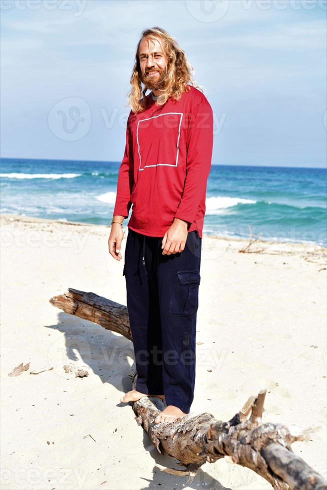 uomo equilibratura su un' log su il spiaggia foto