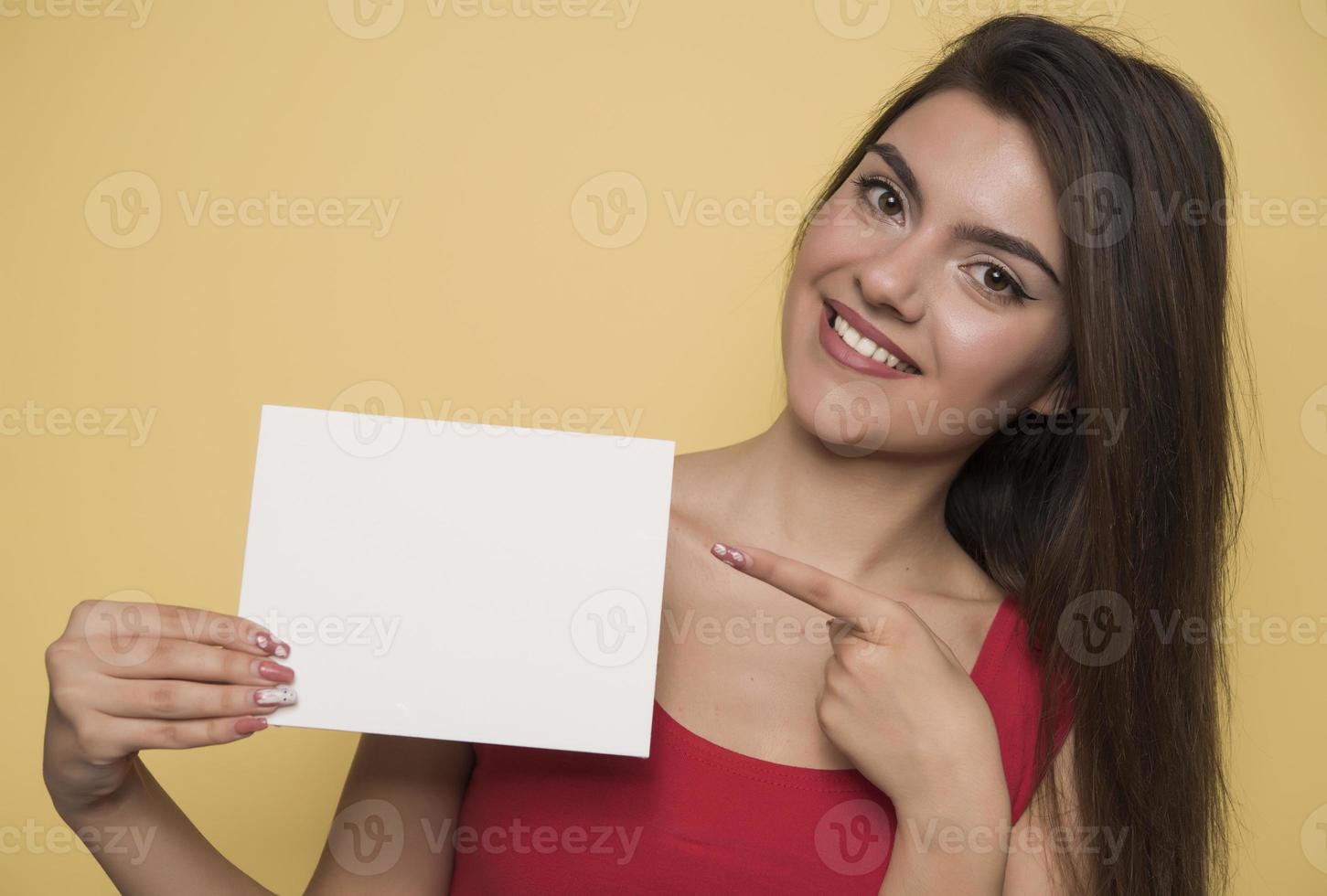 giovane sorridente donna Tenere un' vuoto foglio di carta per pubblicità foto