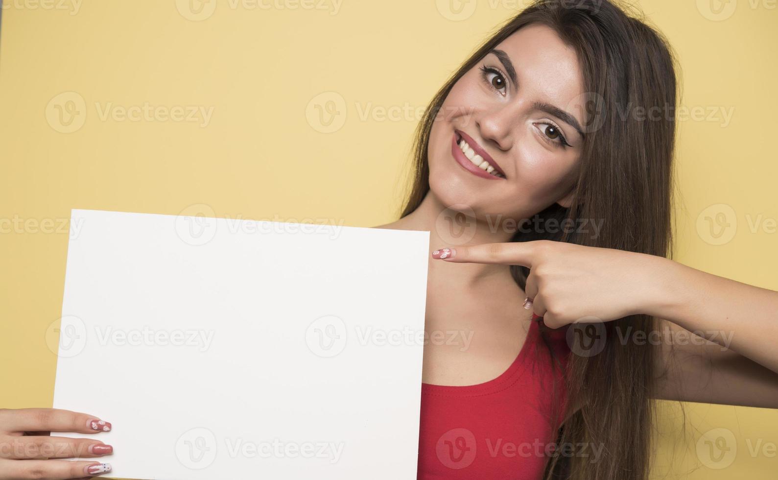 giovane sorridente donna Tenere un' vuoto foglio di carta per pubblicità foto